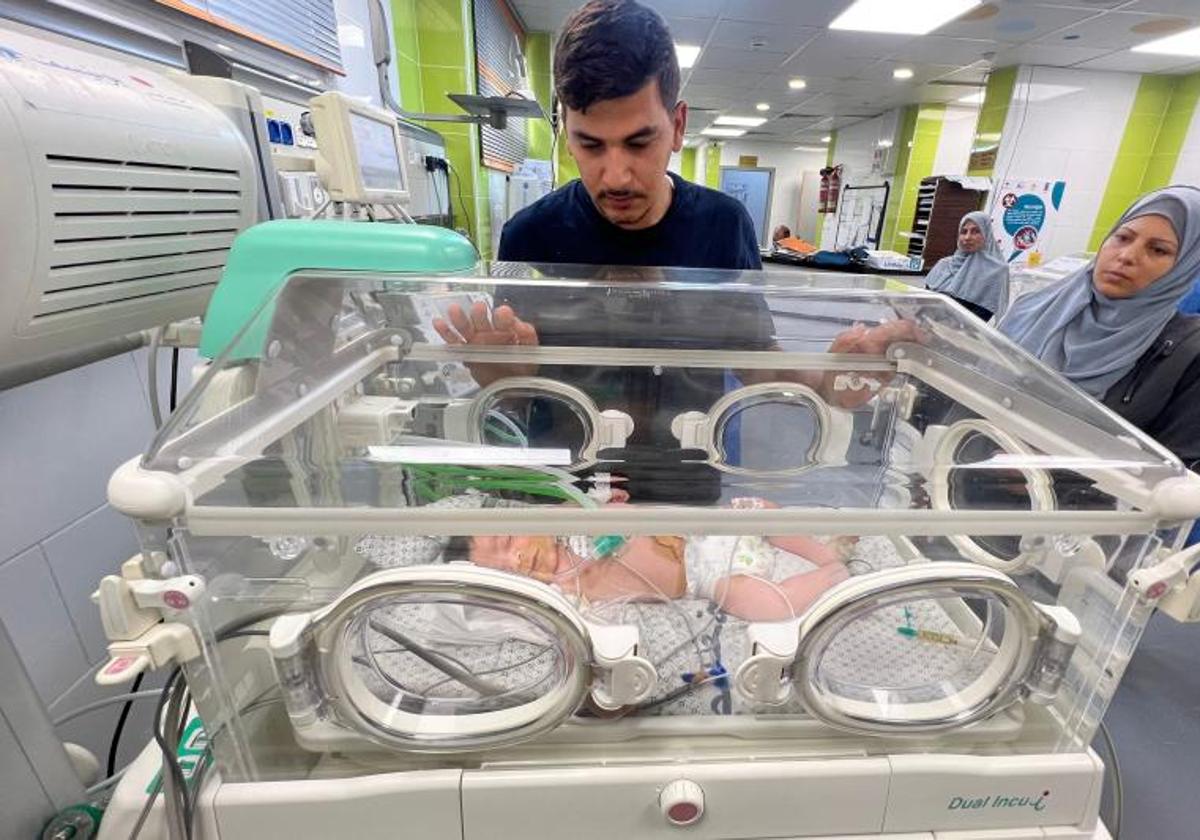 Un padre hace guardia del lado de su hija recién nacida, que recibe cuidados en una incubadora del hospital de Rafah.