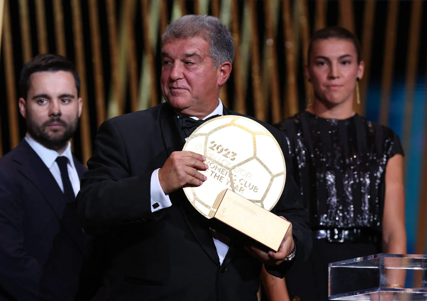 El presidente Joan Laporta sostiene el trofeo que acredita al Barça como club femenino del año en presencia del técnico Jonatan Giráldez y la futbolista Patricia Guijarro.
