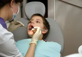 Una odontóloga revisa la salud de los dientes y encías de un niño.