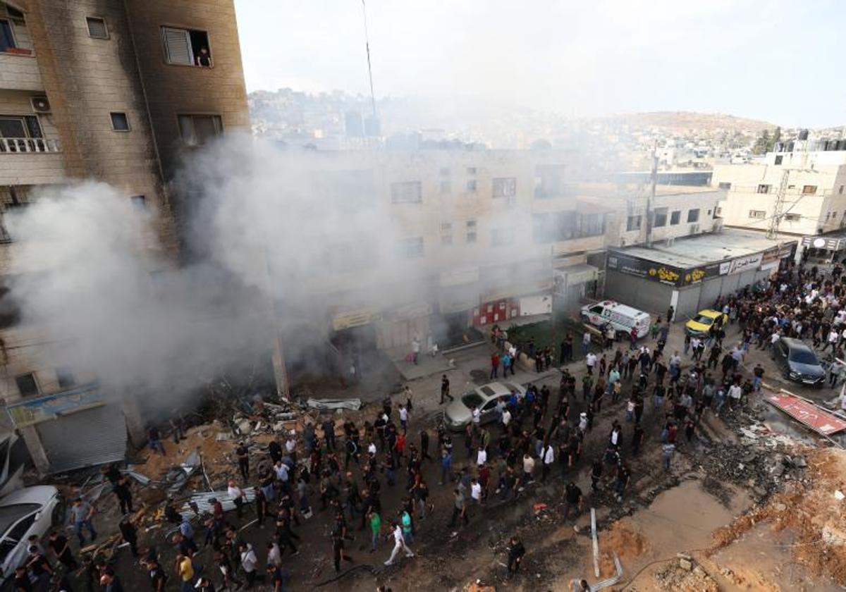 Un grupo de palestinos junto a un edificio dañado en la ciudad de Yenín, en Cisjordania