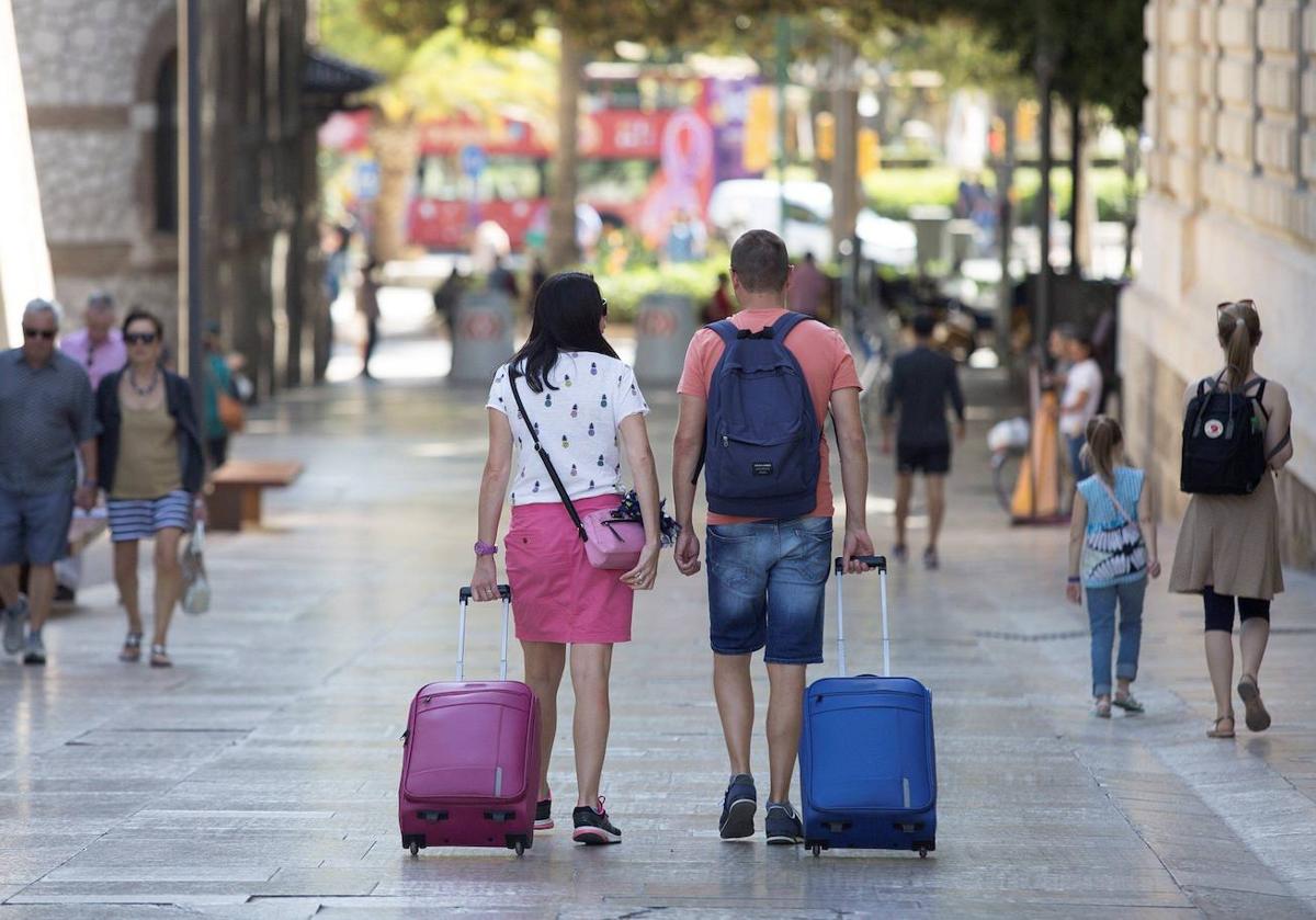 Dos turistas arrastran sus maletas por una calle de Málaga.