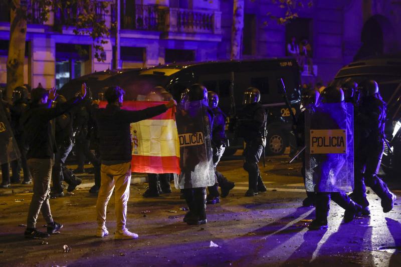 Una persona enseña una bandera de España a la policía durante la manifestación.