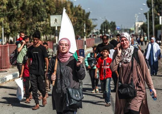 Una joven con una bandera blanca muestra los pasaportes de su familia en su camino desde el norte, huyendo de las bombas, al sur de Gaza.