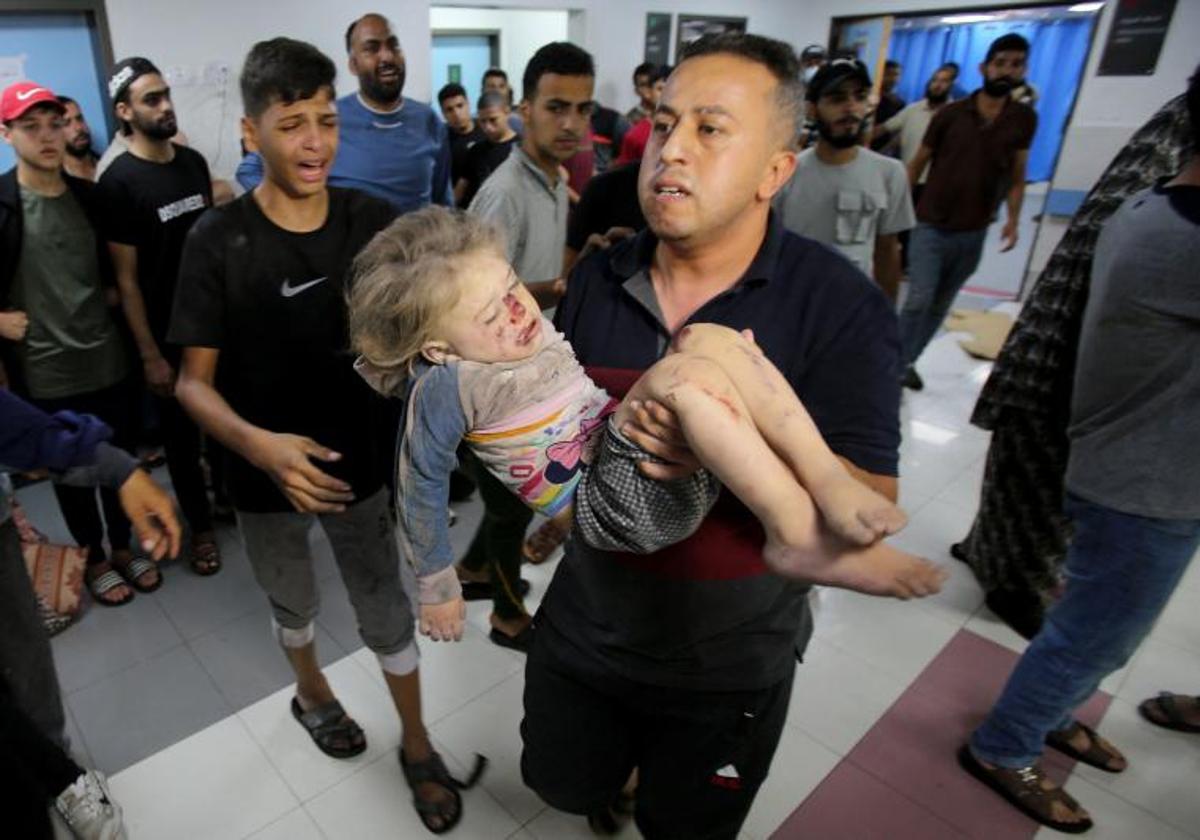 Un hombre traslada al hospital de Al-Shifa a una niña rescatada del interior de un edificio bombardeado en Gaza.