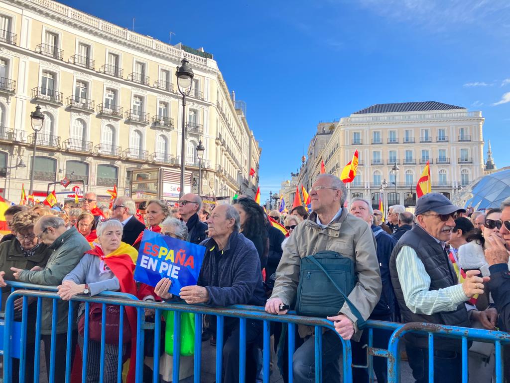 Un hombre con un cartel de España en pie en la manifestación contra la amnistía.