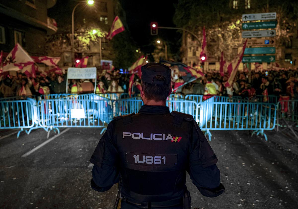 Un policía frente a asistentes a la concentración en contra de la amnistía celebrada este domingo por la noche cerca de la sede del PSOE en Madrid.