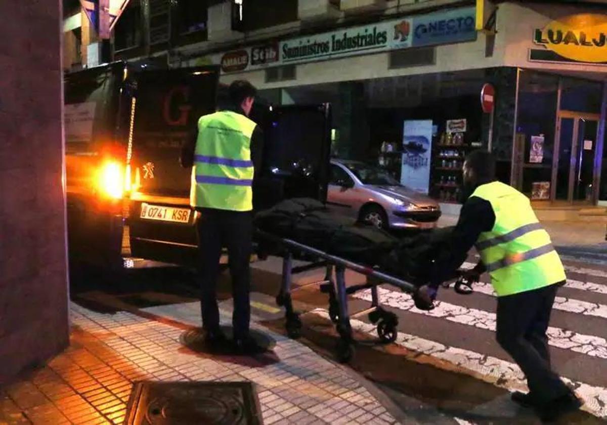 Los servicios fúnebres introducen el cadáver en el furgón.