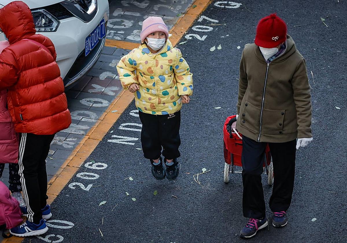 Un niño con mascarilla en la entrada de un colegio en Pekín.