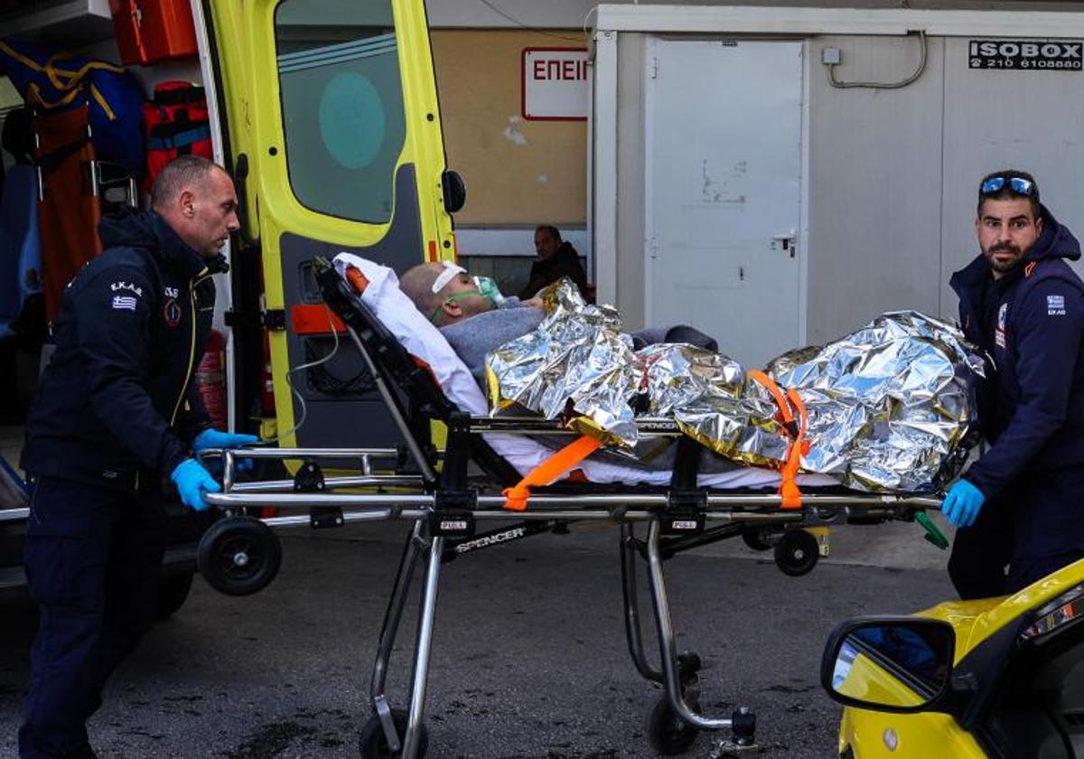 Personal sanitario transporta en camilla al superviviente del carguero que naufragó este domingo en Grecia.