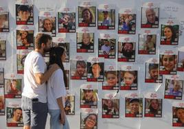 Una pareja pasa junto a las fotos de los rehenes en Tel Aviv.