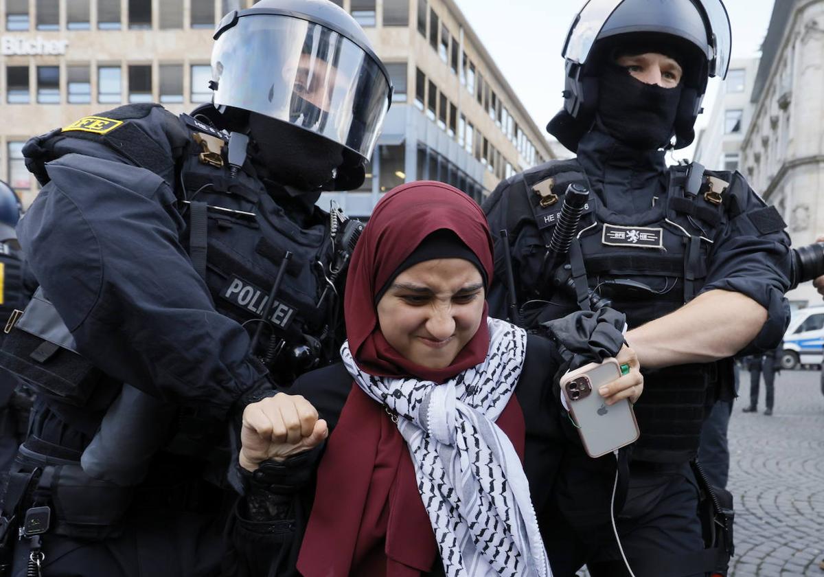 Dos agentes de policía retiran a una participante de una manifestación propalestina en Frankfurt