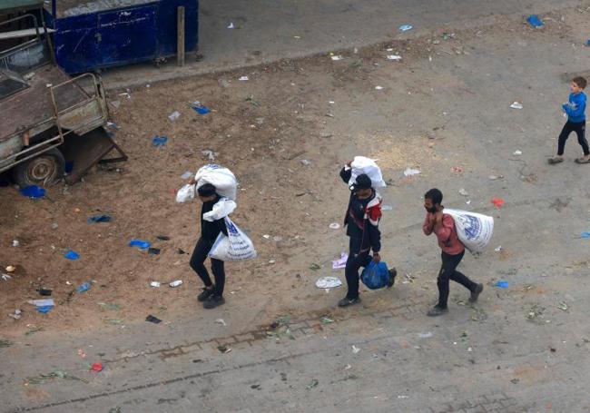 Un grupo de palestinos carga bolsas de alimentos en Rafah, en el sur de Gaza