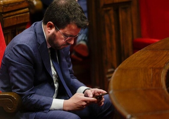 El presidente de la Generalitat, uno de los espiados, consulta su móvil en el Parlament
