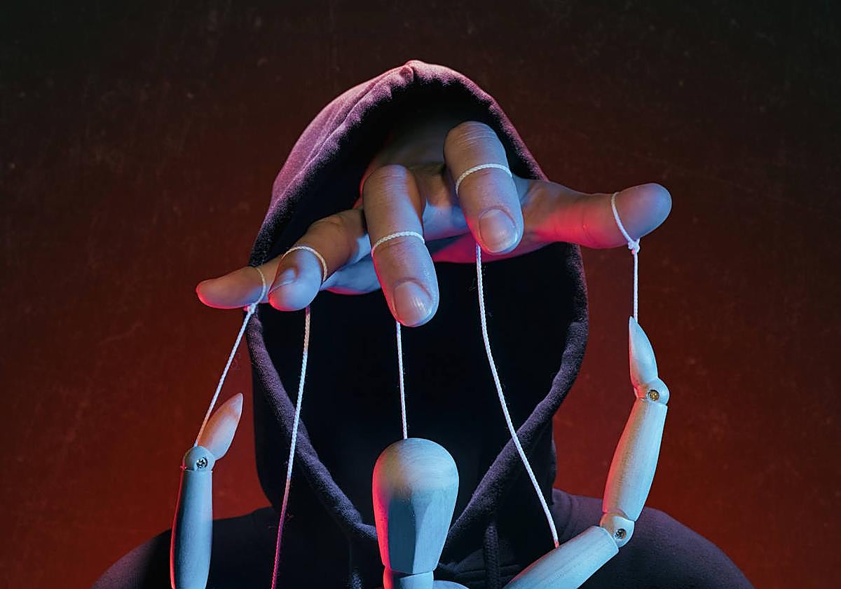 Una mano oculta maneja los hilos de un títere, como metáfora de la manipulación que ejercen los grupos sectarios