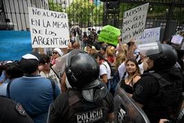 Agentes antidisturbios controlan a un grupo de personas que protesta en Buenos Aires.