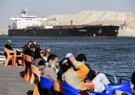 La gente observa cómo un barco cruza el Canal de Suez hacia el Mar Rojo en Ismailia, Egipto.
