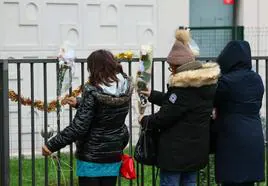 Varias personas dejan flores frente al piso de las víctimas.