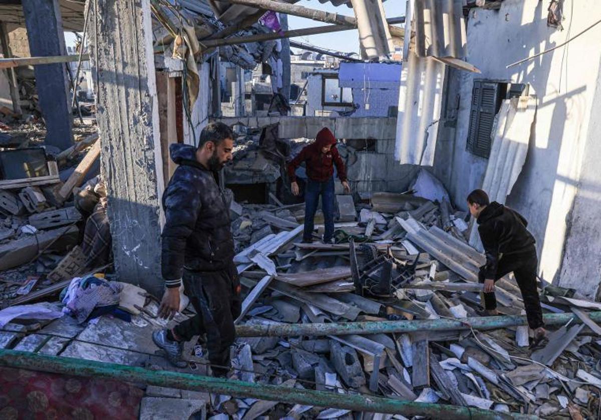 Varios palestinos miran en las ruinas de un edificio.