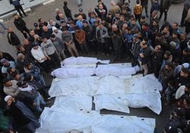 Los familiares de los palestinos que murieron en ataques israelíes reciben los cadáveres de la morgue del Hospital Al-Aqsa para su entierro.