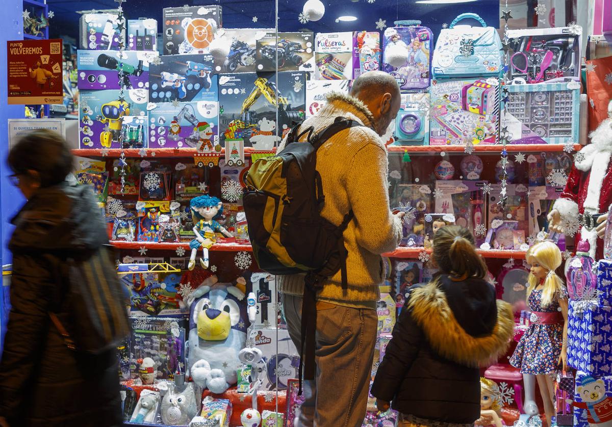 Un padre y su hija observan el escaparate de una juguetería.