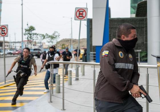 Agentes de policía persiguen a uno de los delincuentes que tomaron los estudios en Guayaquil de la televisión pública.