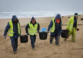 Operarios de empresas contratadas por la Xunta retiran pélets de una playa de La Coruña.