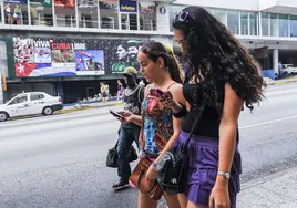 Dos jóvenes caminan por la calle navegando a través de sus móviles.
