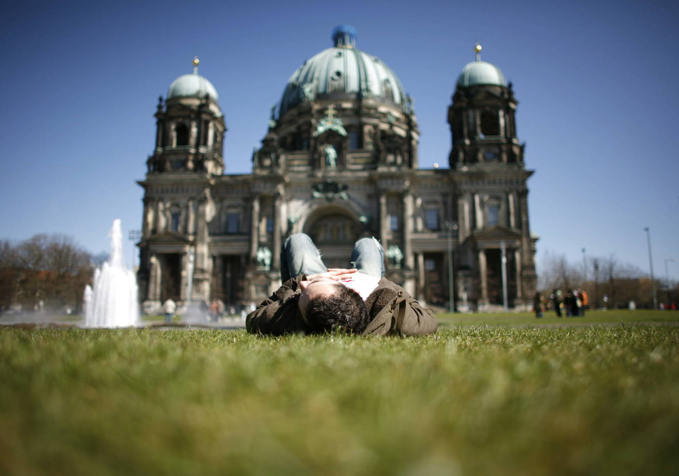 Un hombre toma el sol delante de la catedral de Berlín.