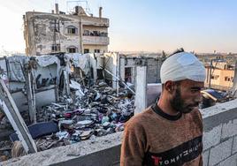 Un hombre herido, de pie junto a los escombros de un edificio destruido en Rafah.