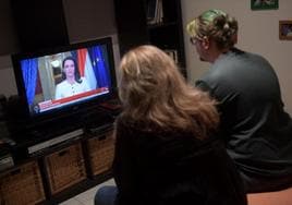 Una madre y su hijo miran la televisión mientras la presidenta de Hungría, Katalin Nóvak, anuncia su dimisión.