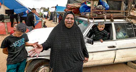 Una mujer llora tras cargar todo lo que aún tiene en un coche para salir huyendo de Rafah.