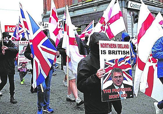 Manifestantes lealistas sostienen carteles y banderas durante una protesta.