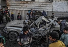 Jóvenes palestinos junto a un vehículo destrozado por un dron israelí en Gaza.