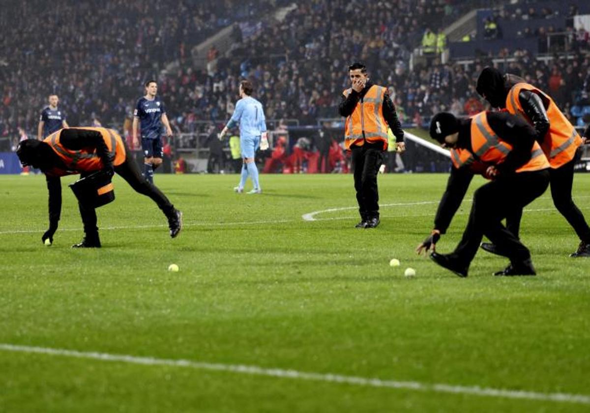 Operarios recogen pelotas de tenis lanzadas por los aficionados a modo de protesta durante el Bochum-Bayern de Múnich.