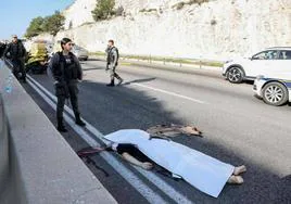 Un miembro de las fuerzas de seguridad israelíes se encuentra junto a un cuerpo en el lugar del ataque, cerca del asentamiento de Maale Adumim.