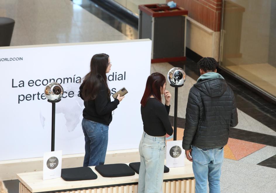 Jóvenes esperan ante un puesto de Worldcoin en un centro comercial.