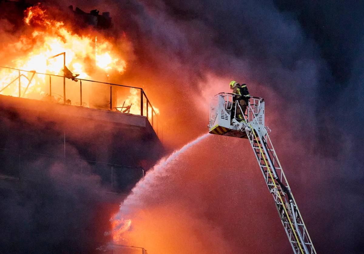 Un bombero echa agua pulverizada sobre la fachada del edificio.