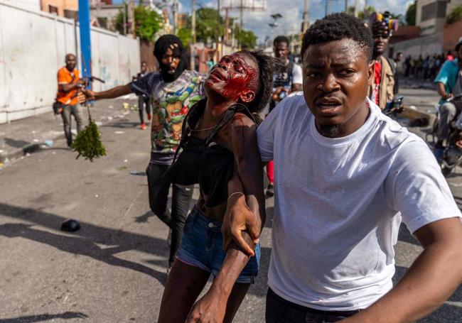 Un hombre asiste a una mujer herida durante una protesta contra Henry.