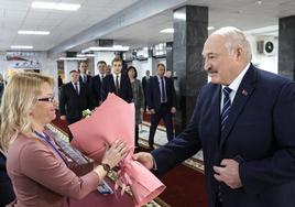 El presidente bielorruso, Alexánder Lukashenko, entrega flores a una miembro de la comisión electoral.