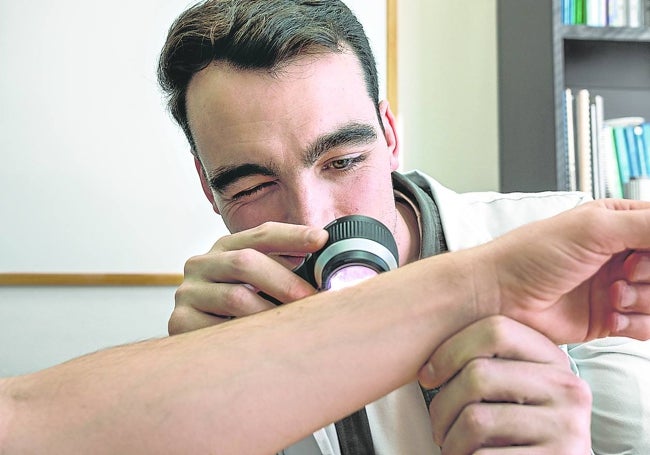 El médico murciano Rafa Escudero, residente de tercer año, observa una lesión cutánea en el brazo de un paciente.