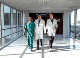 El jefe del servicio de Dermatología en La Paz, Pedro Herranz, camina por un pasillo del hospital 'escoltado' por dos de sus residentes, Sergio López Alcázar, con el 'pijama' verde, y Rafa Escudero.