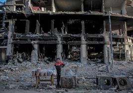 Un joven vendedor palestino espera a sus clientes junto a un edificio en ruinas en Gaza.