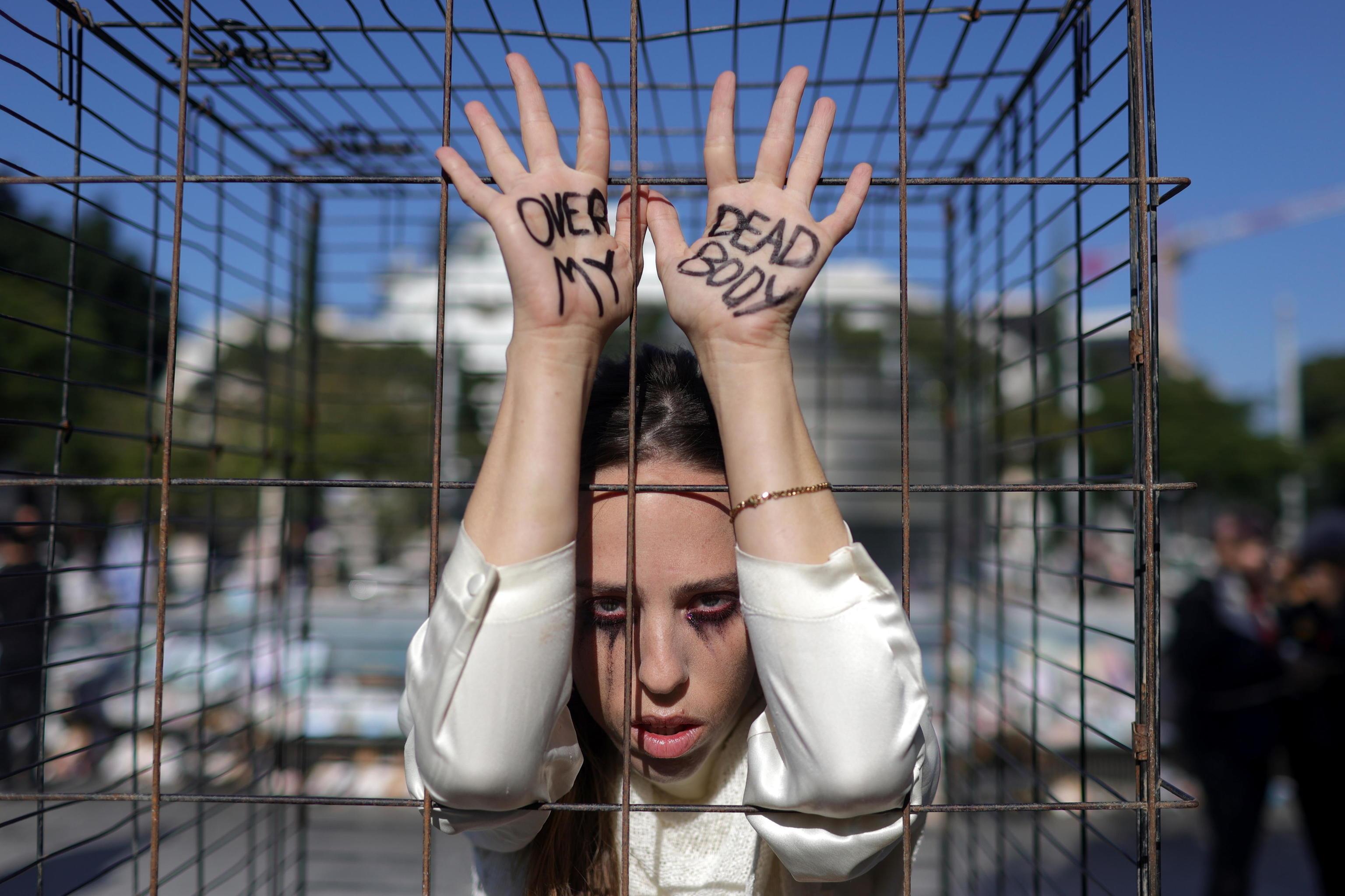 Una joven manifestante en plena protesta dentro de una jaula como las encontradas en los túneles de Hamás para encerrar a los cautivos.