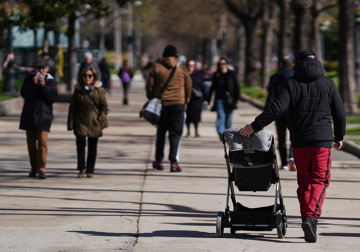 Un padre pasea la silla de su hijo por un parque.