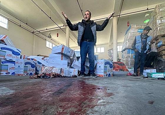 Dos hombres expresan su desesperación al mostrar la mancha de sangre de las víctimas de un ataque contra un centro de reparto de comida.