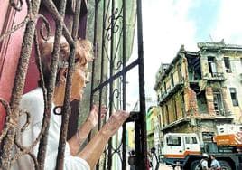 Una vecina se asoma a la ventana de su casa en Centro Habana, repleto de edificios en ruinas.