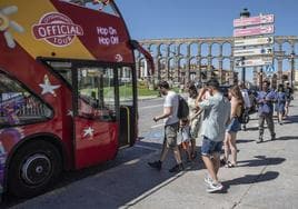 Un autobus turístico recibe decenas de visitantes en Segovia.