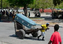 Un hombre acarrea un ataúd por las calles de Puerto Príncipe.