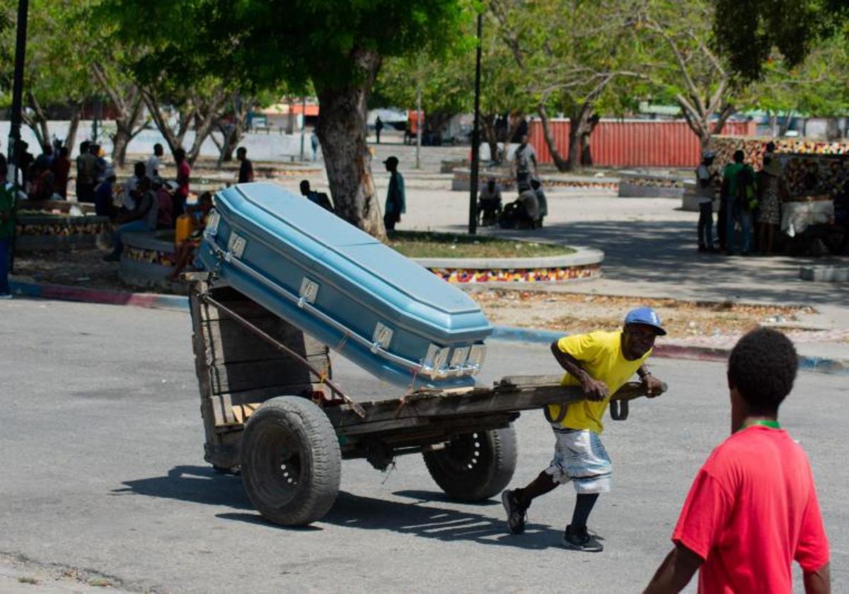 Un hombre acarrea un ataúd por las calles de Puerto Príncipe.