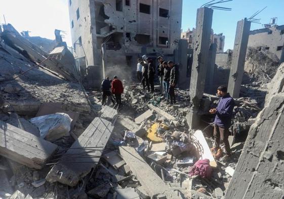 Un grupo de palestinos escrutan los escombros de un edificio bombardeado en el campo de refugiados de Nuseirat.